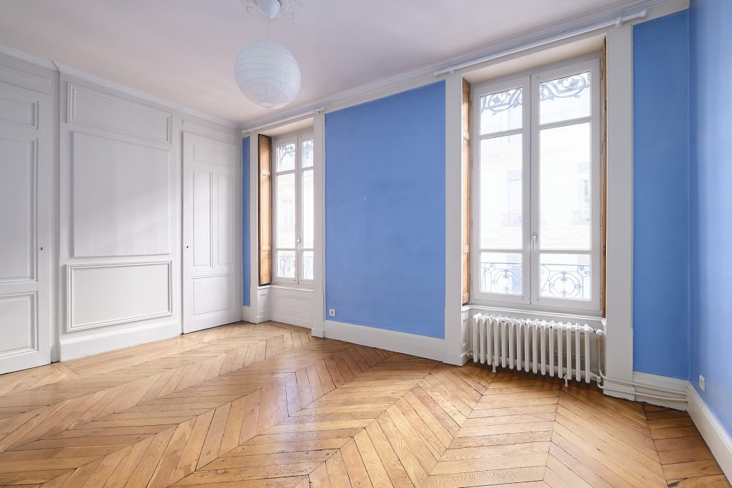 pièce peinte en bleu avec grandes fenêtres et parquet bois massif